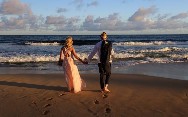 Wedding couple walking away towards the ocean